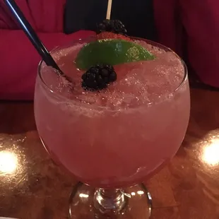 a pink drink with a black berry garnish