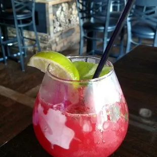 a red drink with lime garnish