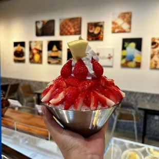 a hand holding a bowl of strawberries