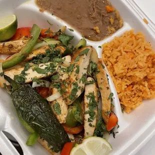 Chicken fajitas served with a grilled jalapeño, rice and beans