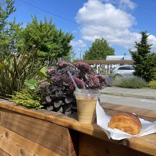 Iced coffee and chocolate croissant on the outdoor patio space facing the Flour Box