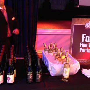 a man standing in front of a table full of wine bottles