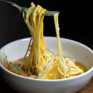 a bowl of noodles being lifted by a fork