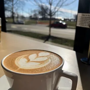 Latte with requisite latte art. By the windows.