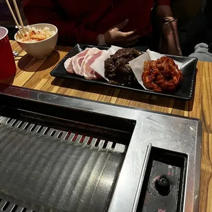 a table with a grill and bowls of food
