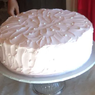 White almond cake with light pink icing and decorative edible pearls. It was delicious!