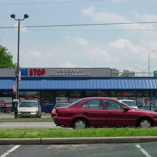 a red car parked in front of a liquor shop