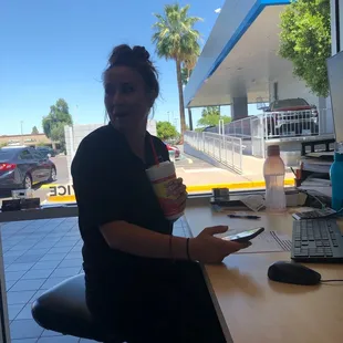 a woman sitting at a desk with a cup of coffee
