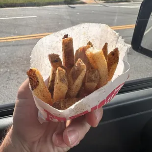 a hand holding a basket of fries