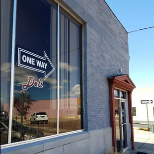 the reflection of a one way sign in a window