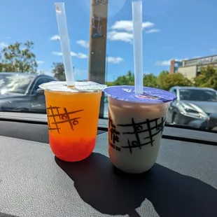 two cups of bubble tea on a car dashboard