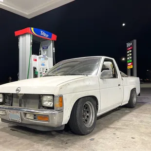 a white pick up truck at a gas station