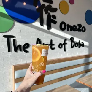 a hand holding a cup of orange juice
