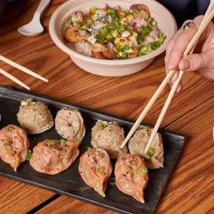 a person holding chopsticks over a plate of food