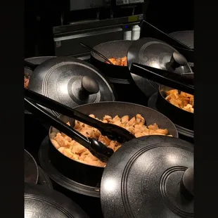 a row of wok pans with food in them