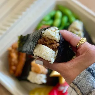 a hand holding a piece of sushi