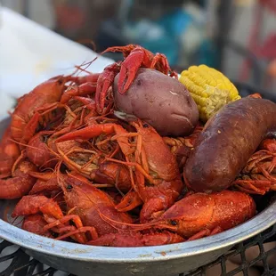 a bowl of crawfish, corn and potatoes