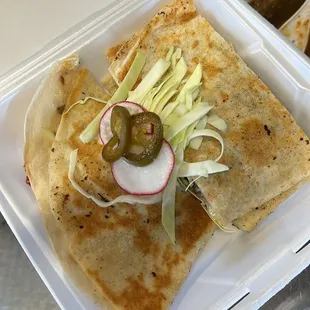 quesadilla on a flour tortilla with melted cheese,meat of your choice and a side of lettuce and sour cream with radish and jalapeño for garn