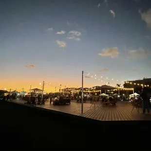 people walking on a boardwalk at dusk