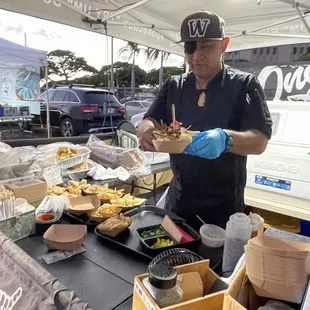 a man preparing food under a tent