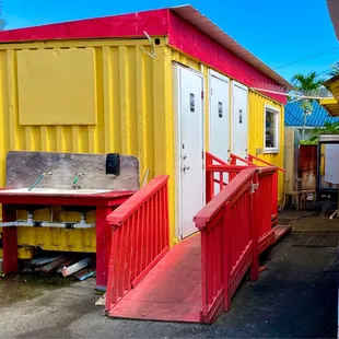 Restrooms in yellow shipping container with hand wash station outside.