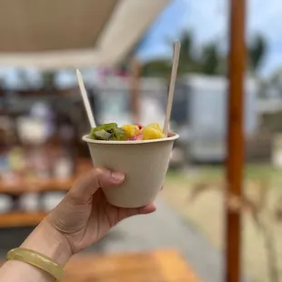 a hand holding a bowl of fruit