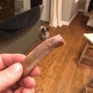 ows a hand holding a piece of meat