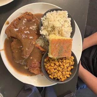 Smothered pork chops with rice, creole corn, and corn bread.