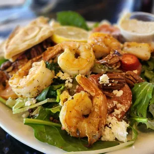 a salad with shrimp, lettuce, tomatoes, and feta cheese