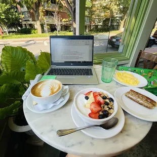 a laptop on a table with breakfast items