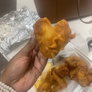 ows a hand holding a piece of fried food