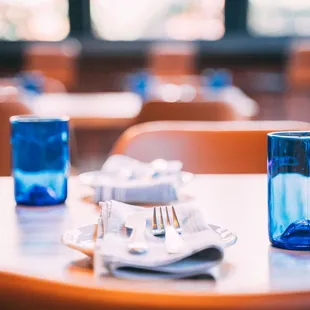 a table with a blue glass and silverware