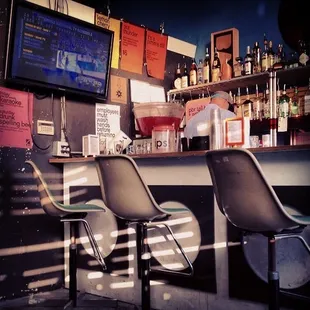 three chairs at a bar with a television in the background