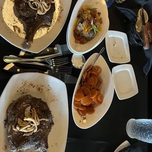 Cowboy steaks with carrots and a baked potato.