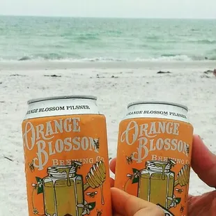 two cans of orange blossom on the beach