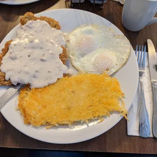Country fried steak and over-easy eggs with hash browns and rye toast.