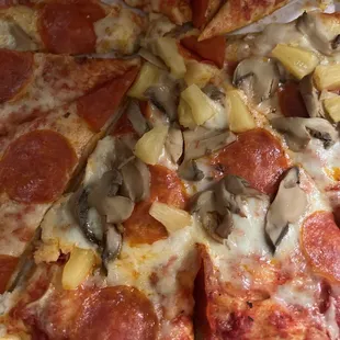 a pizza with pepperoni, mushrooms, and pineapples