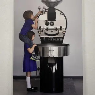 two children at a coffee grinder