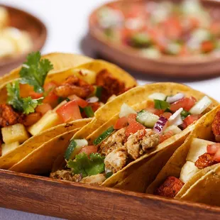 a tray of tacos with a variety of toppings