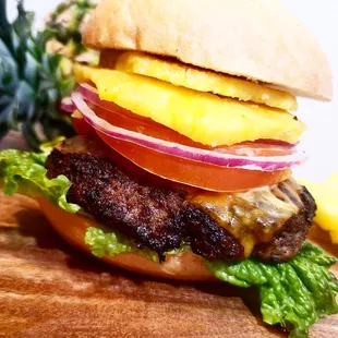 a hamburger with cheese, lettuce, tomato, and onion