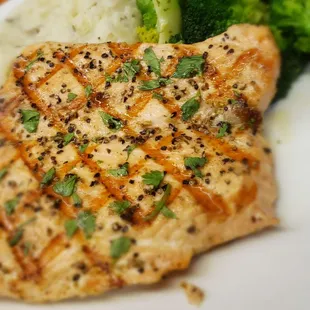 a piece of grilled chicken on a plate with broccoli and mashed potatoes