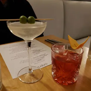a man sitting at a table with two cocktails
