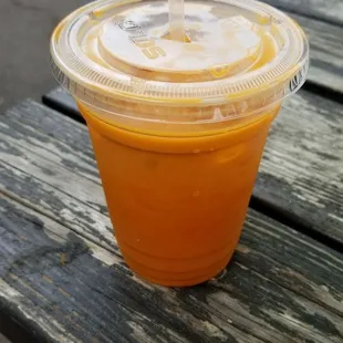 a cup of orange juice on a picnic table