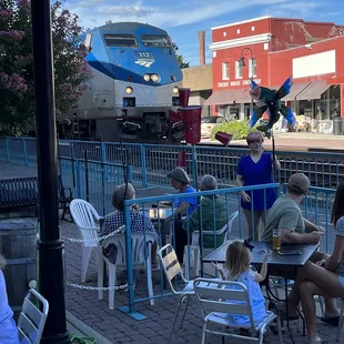 a group of people sitting at tables in front of a train