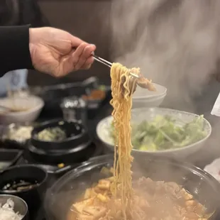 noodles being cooked in a wok