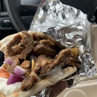 a hand holding a pita sandwich