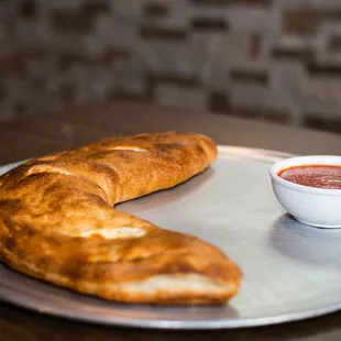a bowl of tomato sauce and a baguet