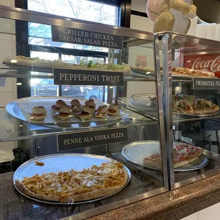 a variety of pizzas in a display case