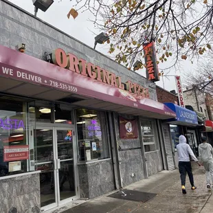two people walking in front of a restaurant