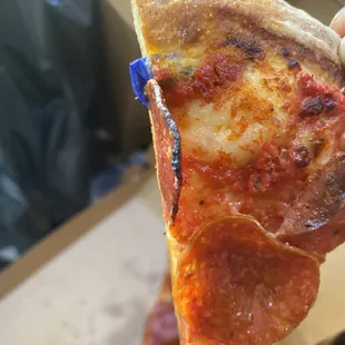 a hand holding a slice of pizza